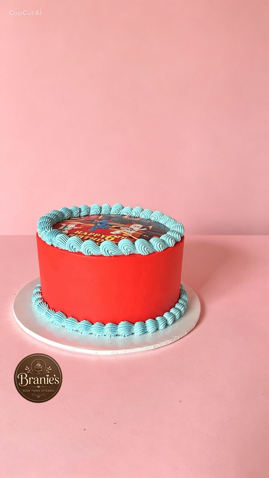 Red cake with blue piping and ninja themed print